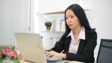 使用笔记本电脑键盘打字的亚洲女商业女性专业用户坐在写字台前，与pc应用软件技术概念一起在网上工作.